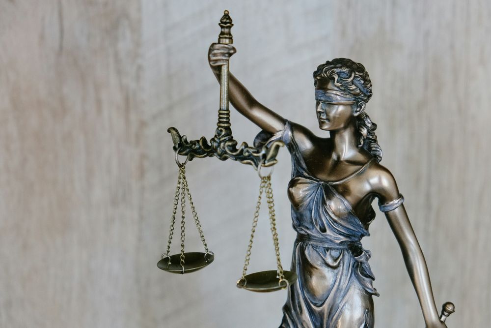 Statue de la justice aux yeux bandés tenant une balance, symbole du droit et de l’équité.